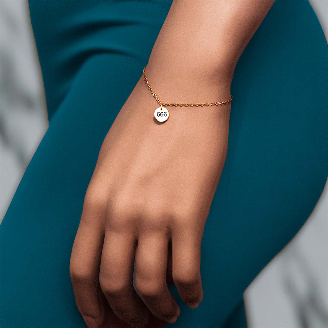 Model hand wearing angel number 666 bracelet gold