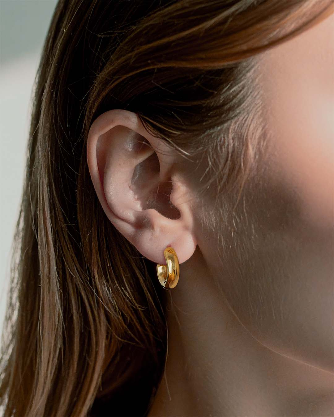 Model wearing Chunky Huggie Hoop Earrings - Gold