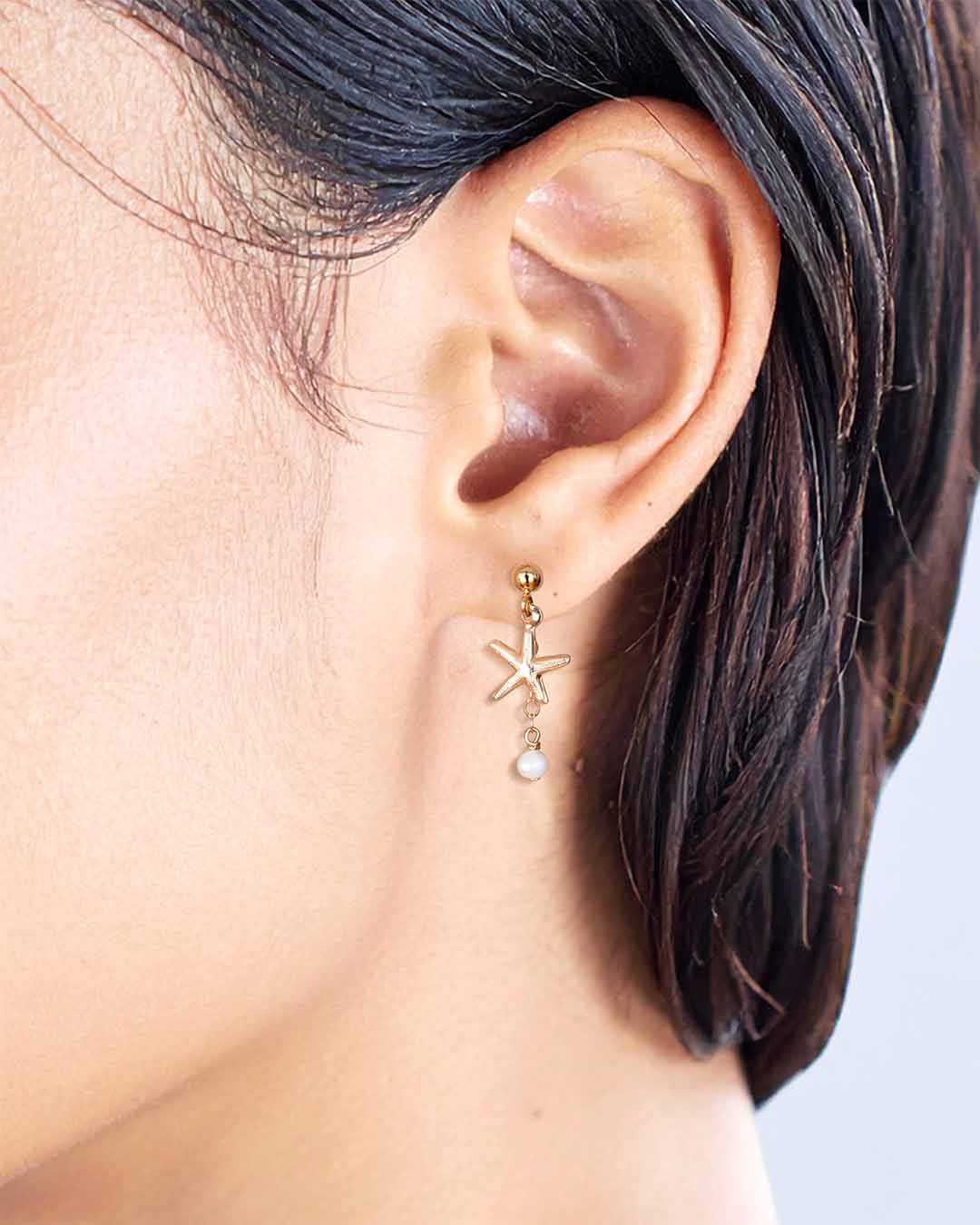 Closeup of model wearing Starfish Drop Earrings - Gold and Pearl
