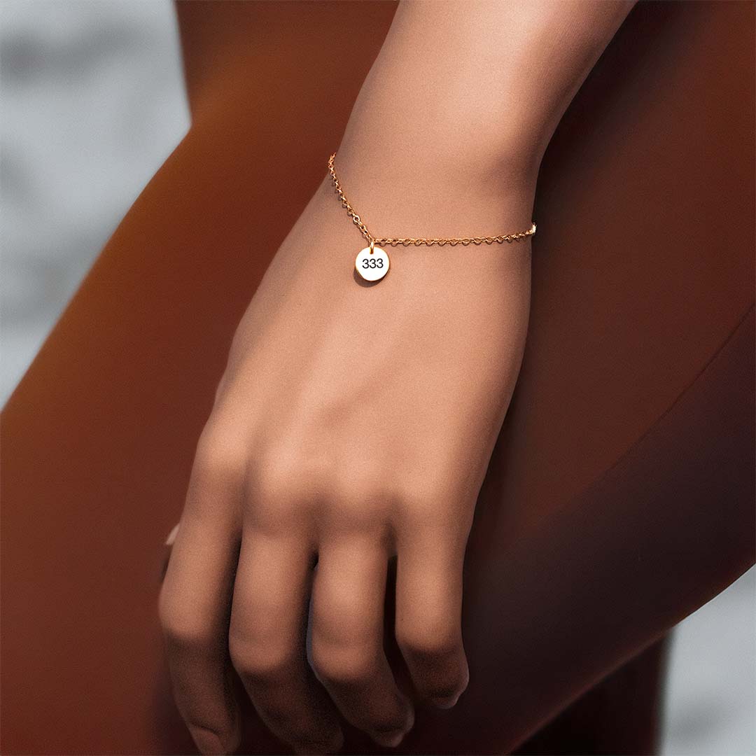 model hand wearing angel number bracelet 333 gold