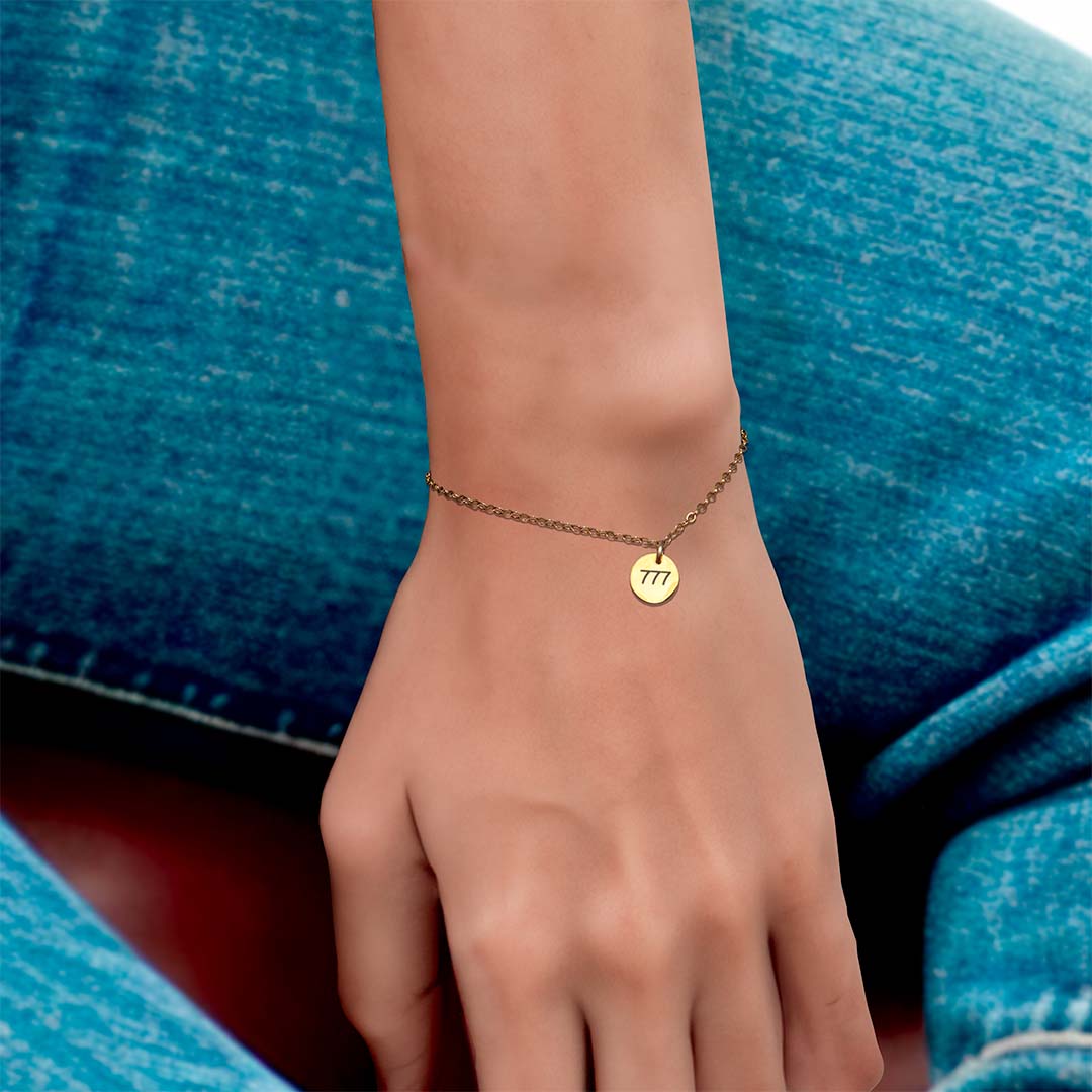 model hand wearing angel number bracelet 777 gold