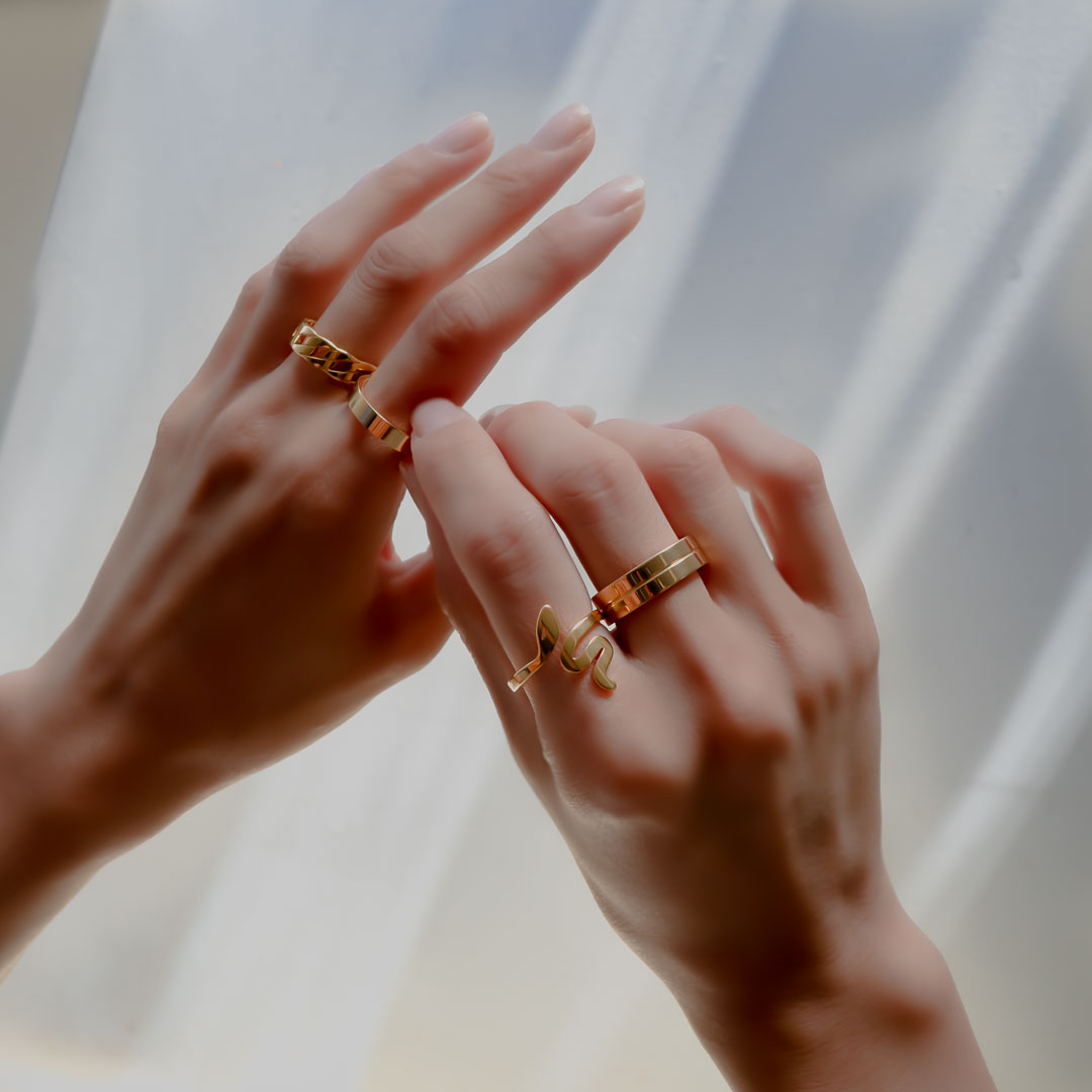 Hands wearing chain band serpent meridian rings gold