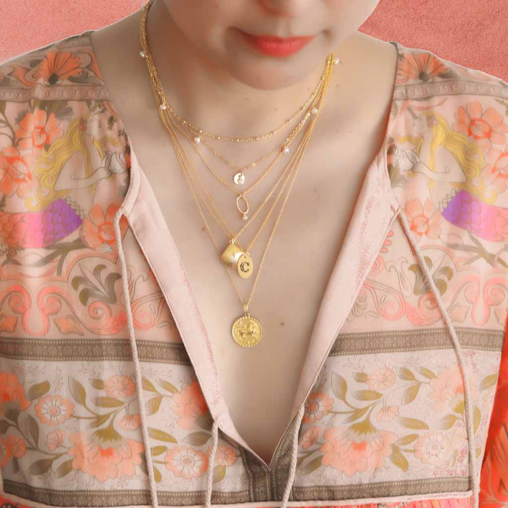 Model wearing Satellite chain, Charmed,Orbit, Love Letter, Seashell and Gold Leo necklaces Gold and Pearl