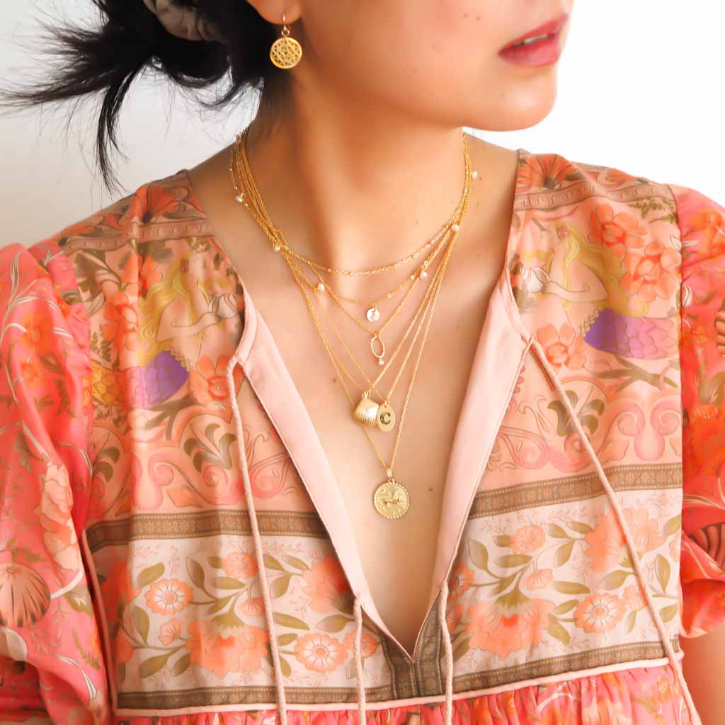 Model wearing Satellite chain, Charmed,Orbit,  Love Letter, Seashell and Gold Leo necklaces Gold and Pearl