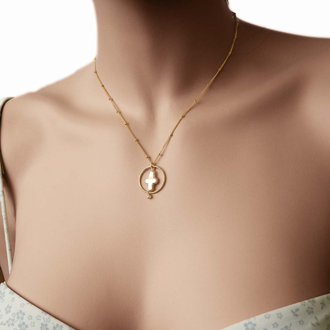 Model wearing Halo Cross Necklace gold pearl