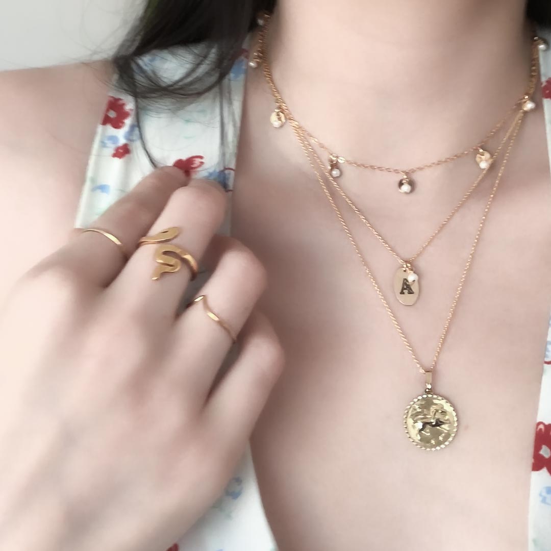 Model wearing  serpent wishbone rings charmed loveletter leo necklaces gold