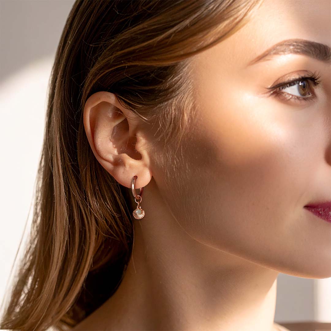 model wearing seashell charmed hoop earrings gold pearl