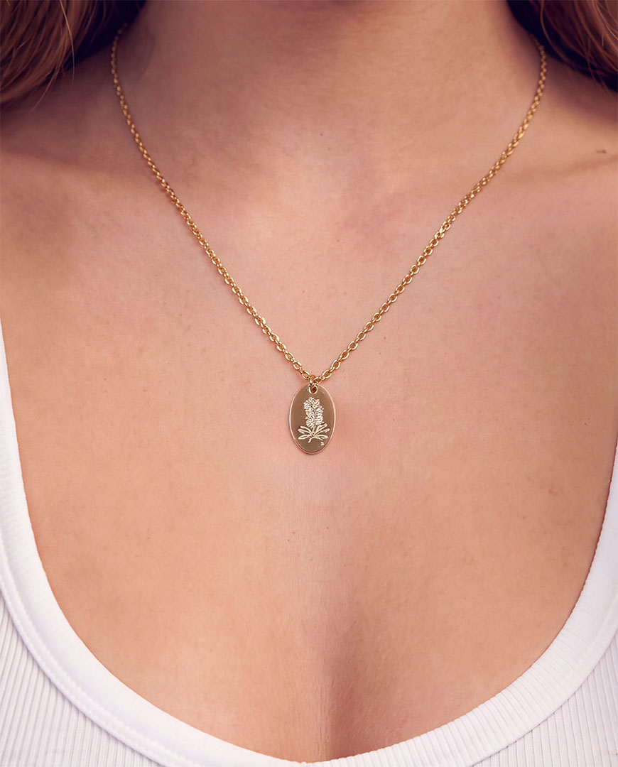 A close-up of a model's neck and chest wearing a delicate gold chain necklace. The Bottlebrush necklace from the Australian Native Birthflower collection by sixD