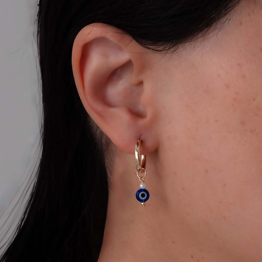 model wearing evil eye charmed hoop earrings gold pearl