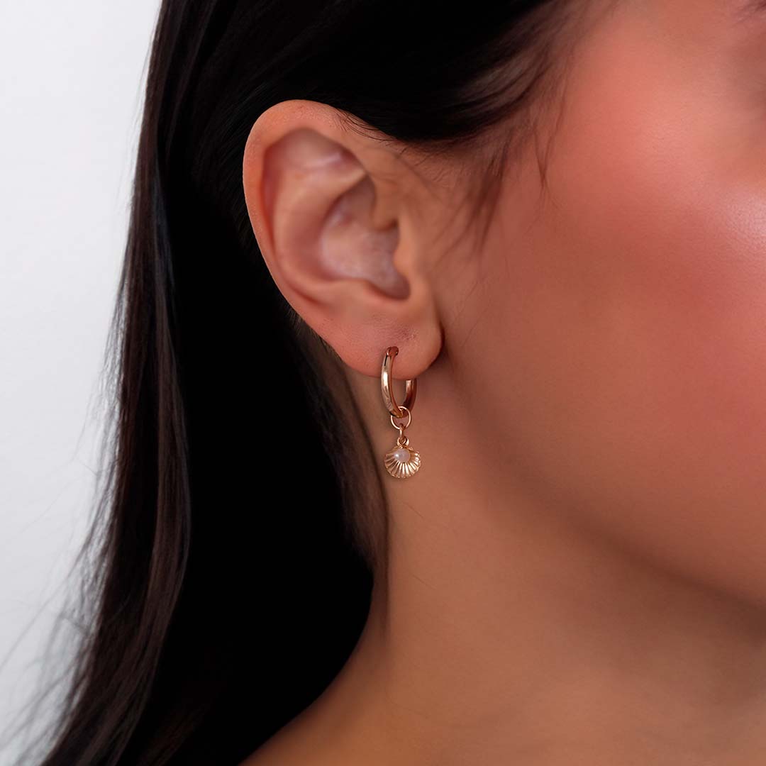 model wearing seashell charmed hoop earrings gold pearl