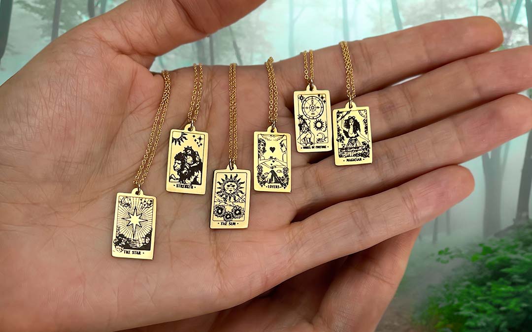 Hand holding tarot gold necklaces