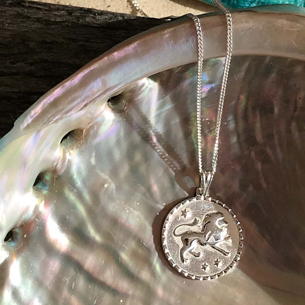 Leo star sign necklace pendant sterling silver jewellery closeup on shell