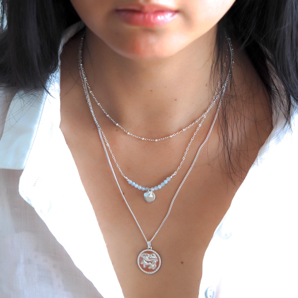 Model wearing The Aries star sign necklace pendant sterling silver jewellery styled with Aura and satellite chain necklaces