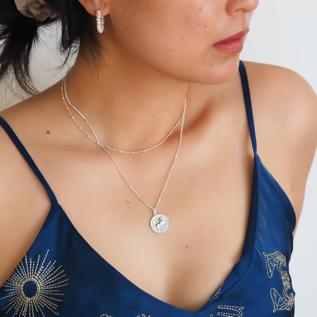 Model wearing Leo star sign necklace pendant sterling silver jewellery styled with satellite chain and enchantment earring
