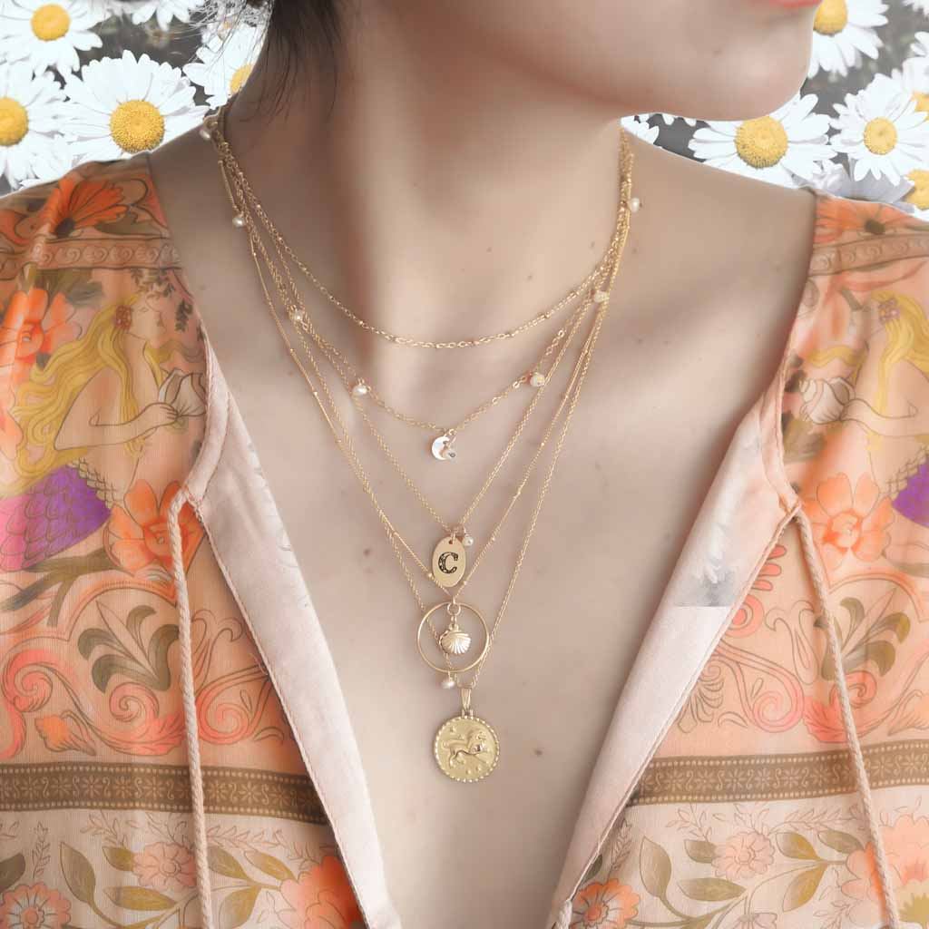 Model wearing Satellite chain, Charmed,Orbit,  Love Letter, Seashell and Gold Leo necklaces Gold and Pearl