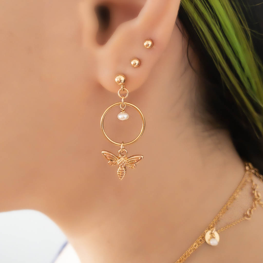 Model wearing Halo Honey bee earrings gold pearl stacked