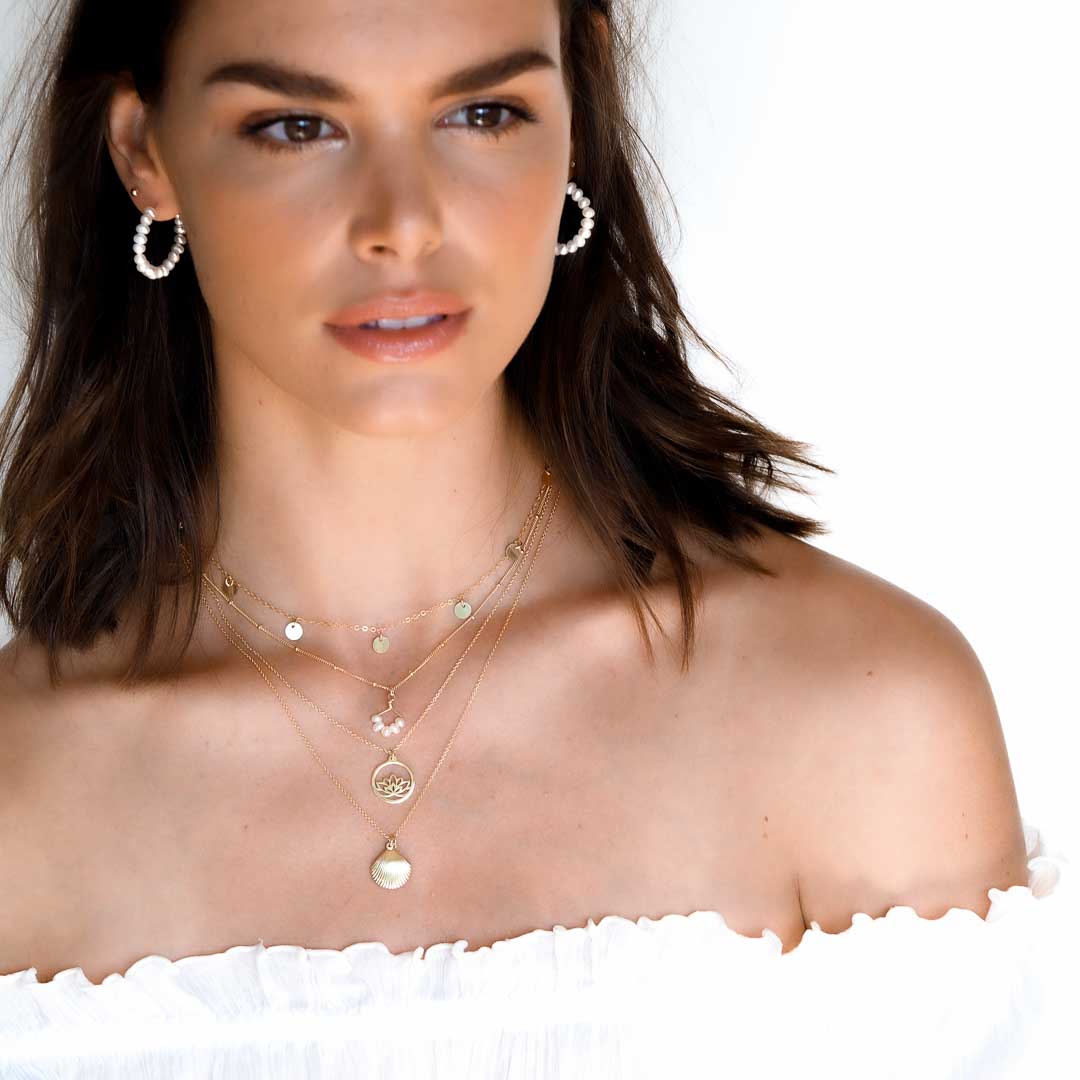 Model wearing Pearl earrings, Charmed,angel 5, lotus, impressions seashore necklaces gold and pearl layered