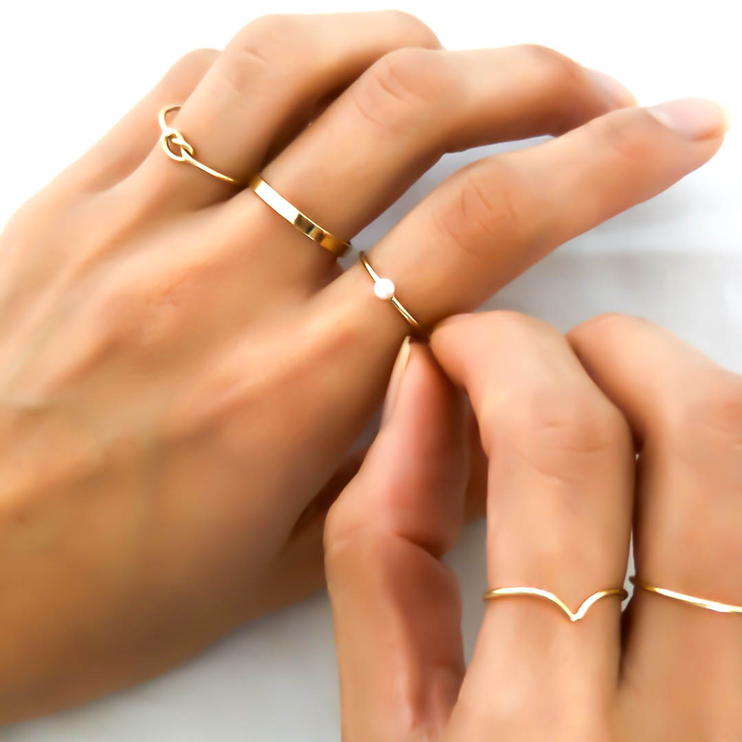 Hand model wearing Knot, band, baby pearl, wishbone rings