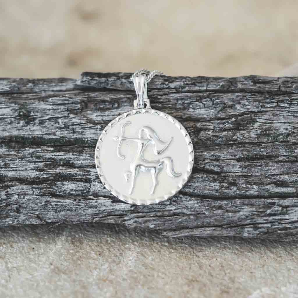 The Sagittarius star sign necklace pendant sterling silver jewellery on wood flatlay