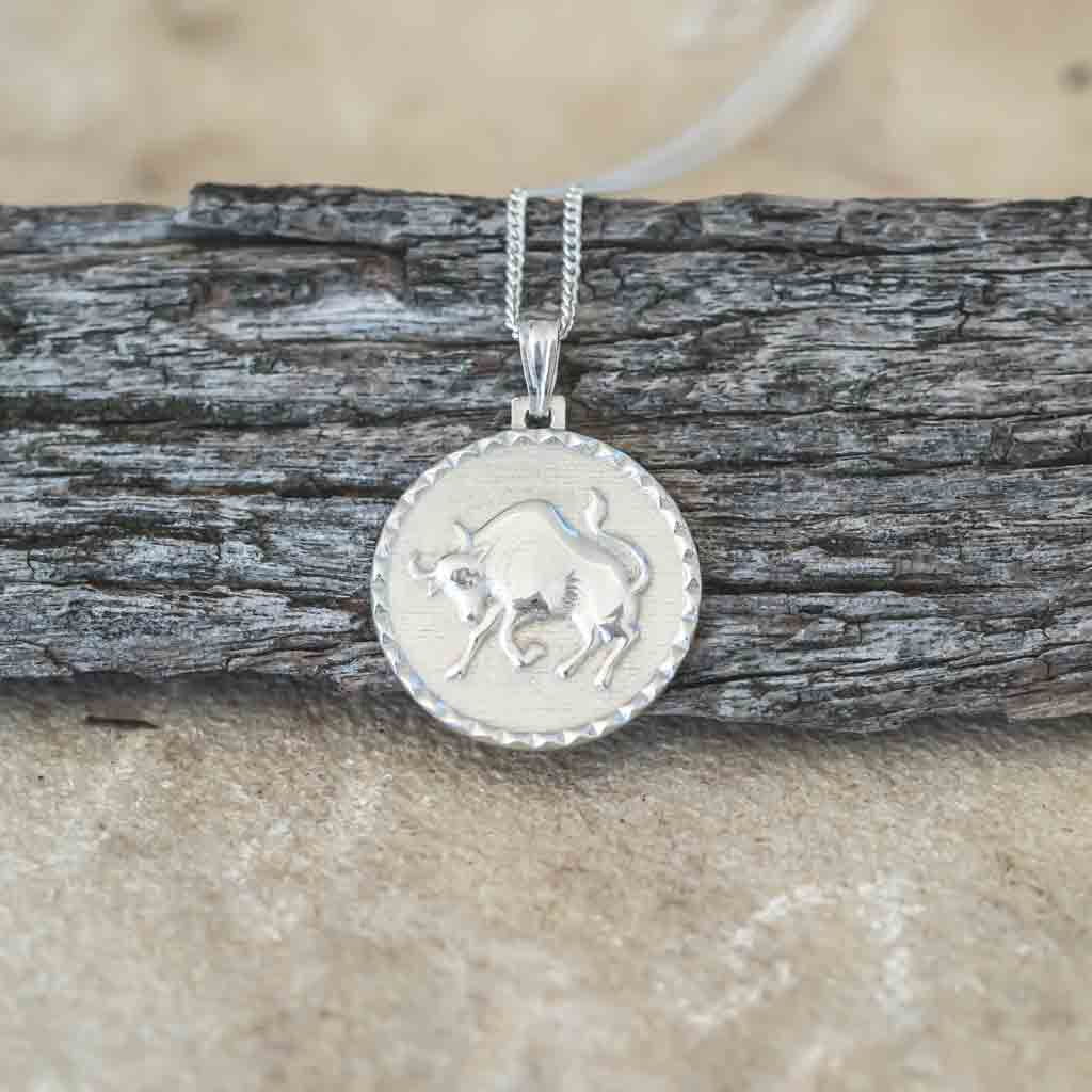 Taurus star sign necklace pendant sterling silver jewellery on wood flatlay