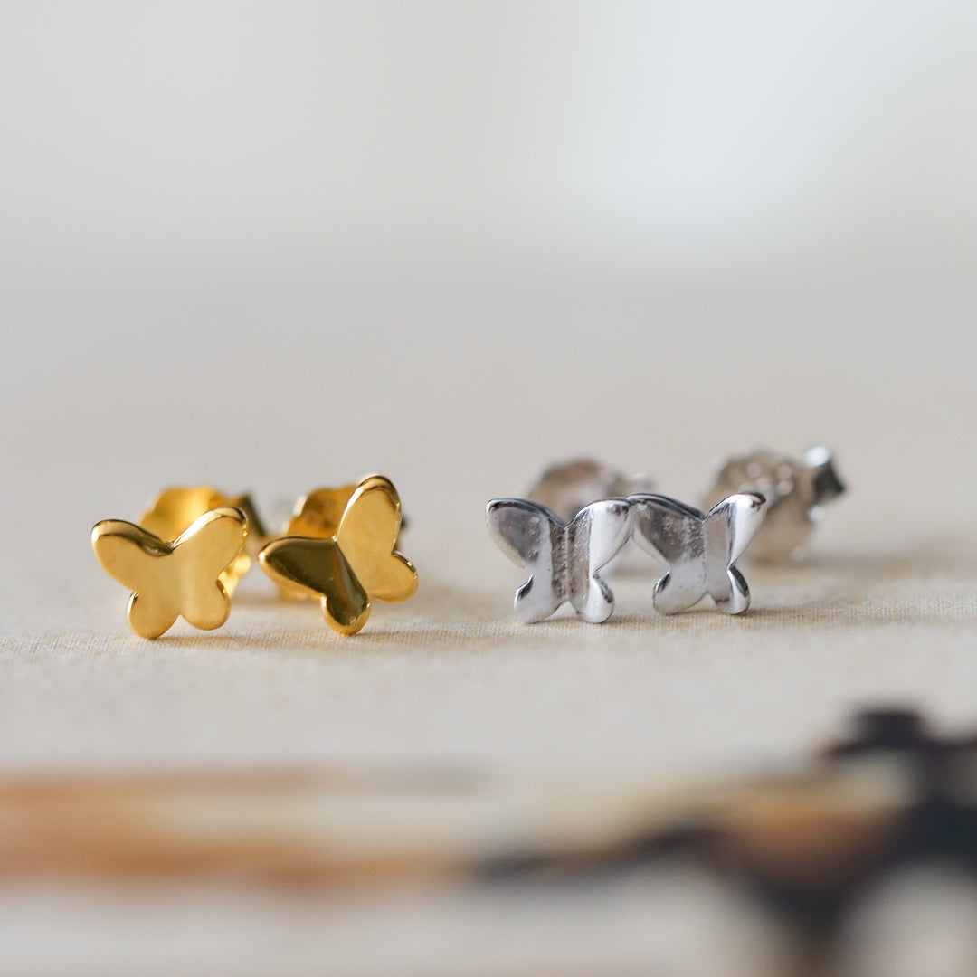 butterfly stud earrings gold silver flatlay