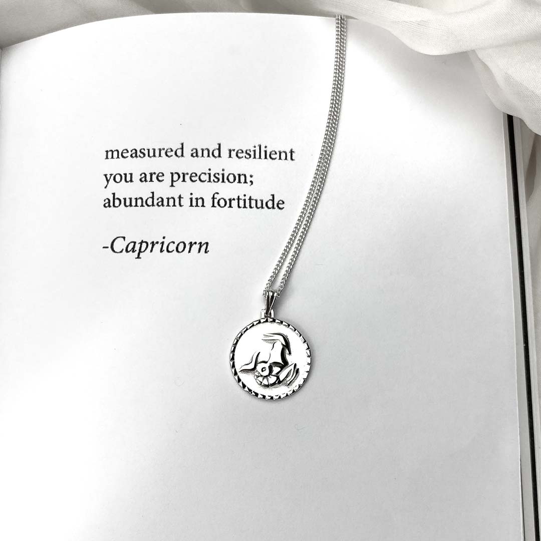 capricorn star sign necklace pendant in sterling silver jewellery on poetry book