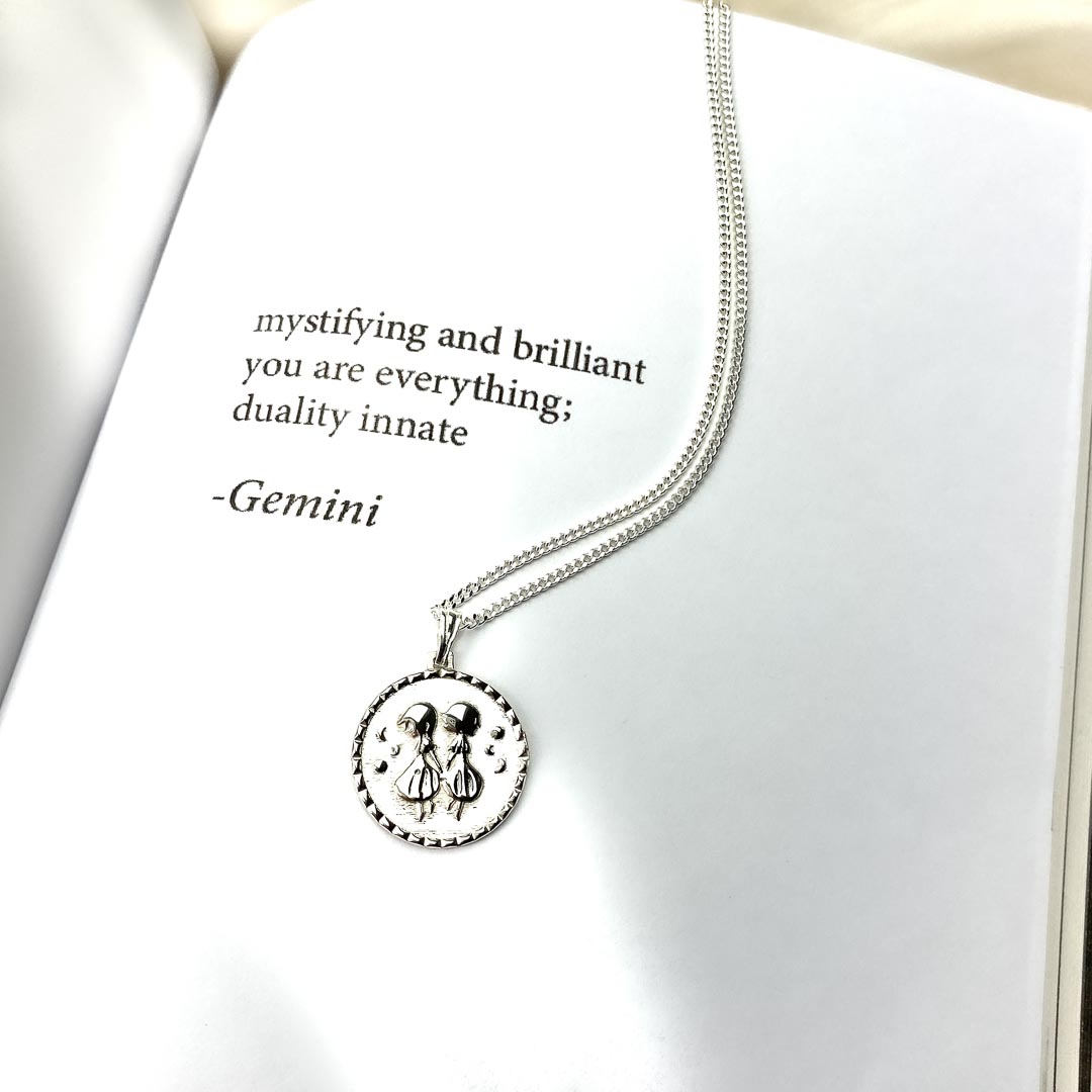gemini star sign necklace pendant in sterling silver jewellery on poetry book