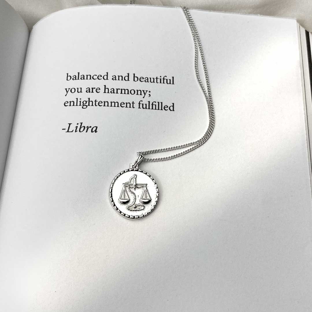 Libra star sign necklace pendant sterling silver jewellery on book with poetry
