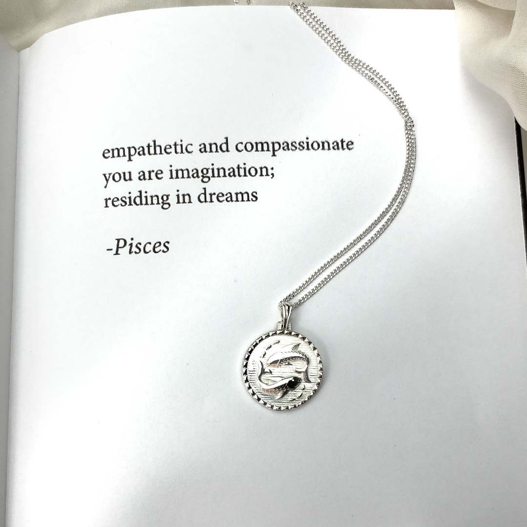 The Pisces star sign necklace pendant sterling silver jewellery on book with poetry