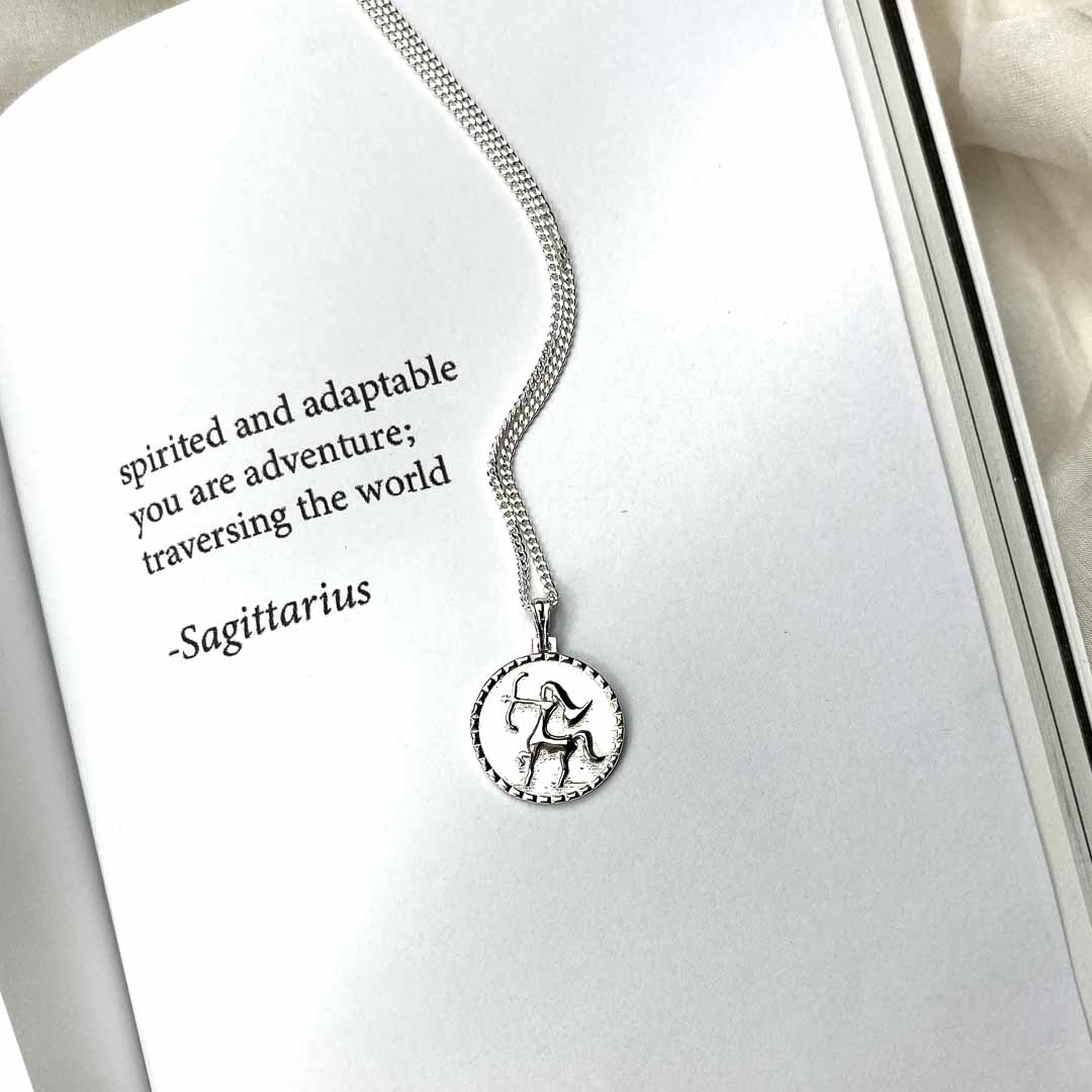 The Sagittarius star sign necklace pendant sterling silver jewellery on poetry book