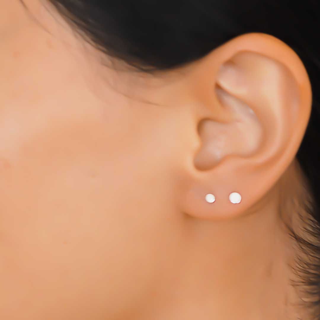 Model wearing 2 Flat dot stud earrings closeup