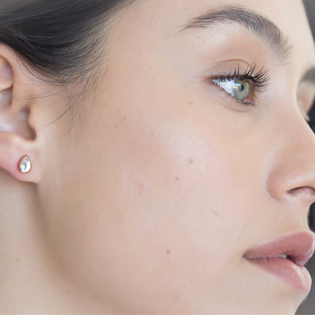 model wearing teardrop stud earrings rose gold clear quartz closeup